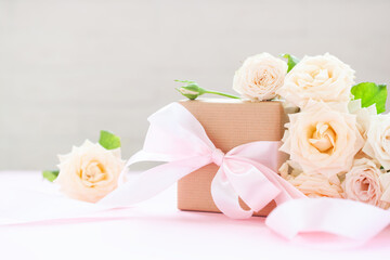 Gift box wrapped in brown paper with pink roses on pink background.