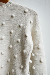 White knitted sweater hanging on a hanger