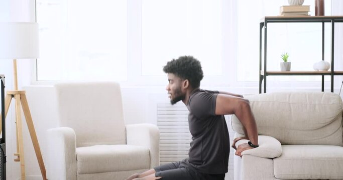 African American Man Doing Triceps Exercise On Sofa At Home