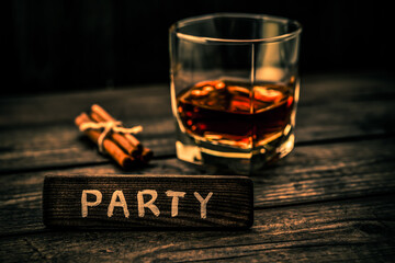 Glass of brandy with cinnamon sticks tied with jute rope and the wooden plank on it is an inscription 