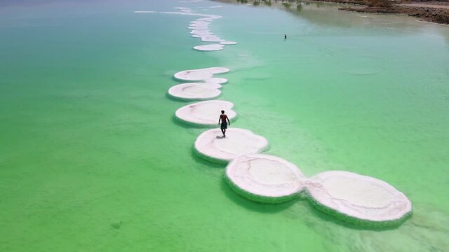 Aerial Lockdown Shot Of Tourist Walking On Salt Formation At Dead Sea During Sunny Day