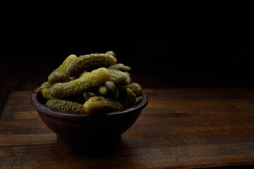 A cup of crispy pickled cucumbers stands on a wooden cutting board. Salted cucumbers.