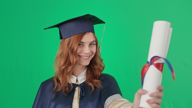 female graduate in academic dress kisses and diploma in hands and rejoices at graduation, pre-keyed footage