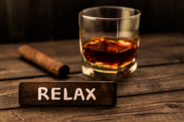 Glass of brandy with cuban cigar and the wooden plank on it is an inscription 