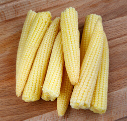 Young corn on a wooden cutting board . Delicious baby corn.