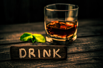 Glass of brandy with mint sprig and the wooden plank on it is an inscription 