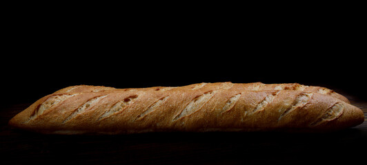 Fresh crispy baguette on a dark background.