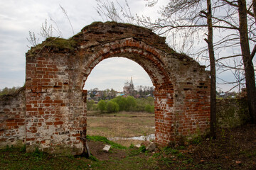 Old red brick wall gate and view to the church, river, countryside in cloudy spring day