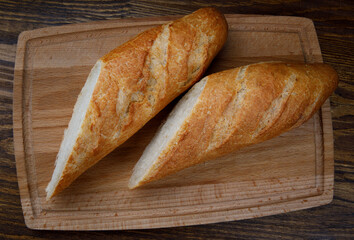 Sliced fresh crispy baguette on a wooden cutting board. art bread.