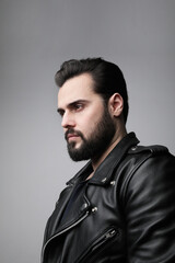 Side portrait of bearded brutal man looking aside. Posing on the white wall.