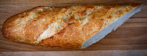 Half a baguette on a wooden cutting board. art bread.
