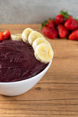 Açai, Brazilian frozen açai berry ice cream bowl with strawberries and bananas. with fruits on wooden background. Summer menu front view