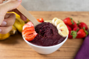 Açai, Brazilian frozen açai berry ice cream bowl with strawberries and bananas. with fruits on wooden background. Summer menu front view