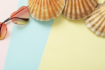 summer vacation concept with heart shape sunglasses and sea shells on pastel background