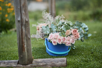 A bucket of flowers laying on grass, light pink roses