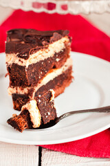 Dark chocolate cake with Coffee slice with chocolate buttercream frosting on a white plate.Selective focus