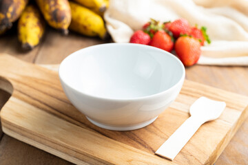 Empty white bowl with fruits on wooden table background