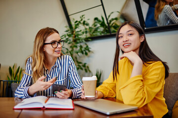 Smiling diverse friends communicating in cafeteria in daytime