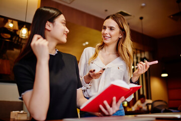 Multiracial happy women speaking about work with notebook