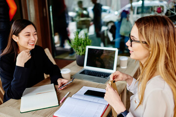 Fototapeta premium Happy multiracial colleagues discussing project while sitting on terrace of cafe