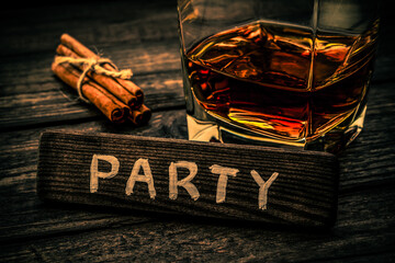 Glass of brandy with cinnamon sticks tied with jute rope and the wooden plank on it is an...
