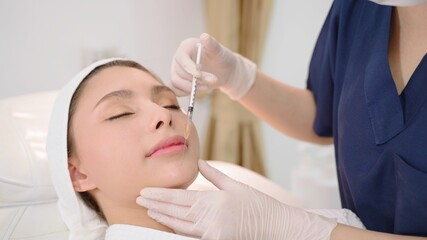 Beautician makes botox injection in the face. beautician makes a treatment procedure to the patient. A beautician gives injections to a woman's face.