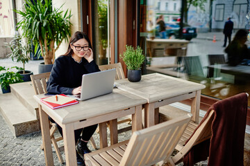 Asian lady working remotely on computer on veranda