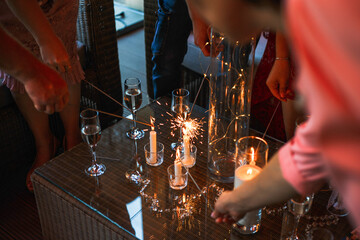 party members light sparklers from candles