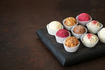 Chocolate, fruit and nut truffles on a dark brown background. Homemade candy or energy balls.