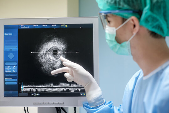 Doctor wears sterile uniform and uses Intravascular ultrasound imaging (IVUS) machine at cardiac catheterization laboratory room.