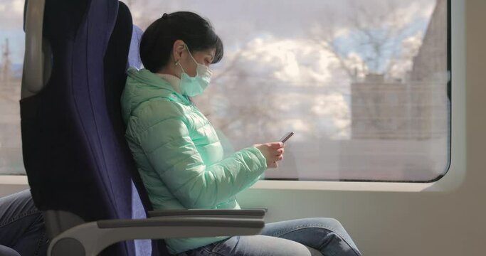 Woman wearing a protective medical face mask rides on a train during the covid 19 quarantine.