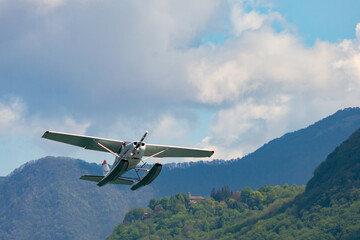 Fototapeta na wymiar A seaplane after the take off flying over the waters of Lake Como, Italy. This airplane take tourists for a tour of the entire lake. If you plan a travel in Como do not miss it.