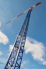 Steel isolated crane in a building construction site to build skyscaper. Vertical photo. Blue sky on the background.