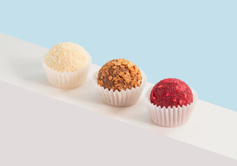 Homemade candies with coconut, dried fruits and nuts on a blue background. Geometric composition with truffles. Isometric view.