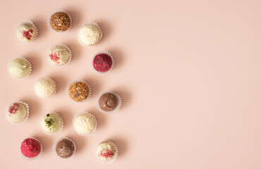 Fototapeta na wymiar Assorted candies with chocolate, karkade, coconut and nuts on a pastel pink background. Truffles or energy balls. Copy space, top view
