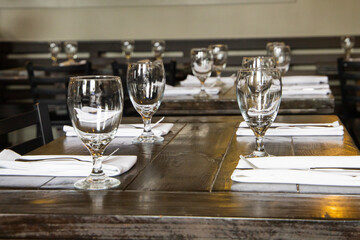 A water glass and a silverware setting for four on a wood table at a high end restaurant