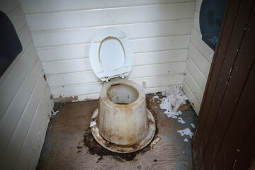 Dirty disgusting smelly dry composting toilet with toilet paper, camping in mountains concept