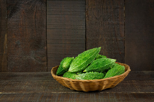 Bitter gourd or bitter melon in basket on wooden background. Scientific name is Momordica charantia. As a whole food and herbs for treating diseases.