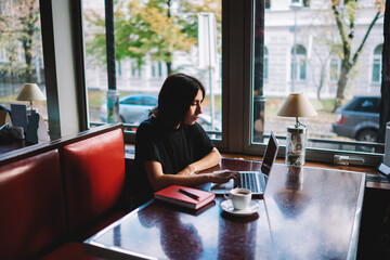 Serious woman working on laptop in cafeteria