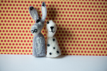 a grey donkey and a white and brown spotted dog finger puppet posing against a red polk dot and...