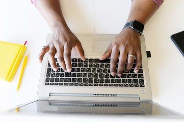 A male hands on the laptop keyboard. Top view an African-American guy is typing email, programmer is develops software, cropped photo, a face is not visible, close-up picture - obrazy, fototapety, plakaty