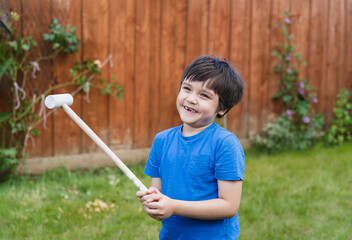 Portrait active young boy playing with wooden hammer toys in the garden, Positive child boy playing outdoor in sunny day spring or summer.