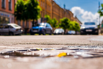 Sunny day after rain in the city, parked in the street car. Close up view of a hatch at the level of the asphalt