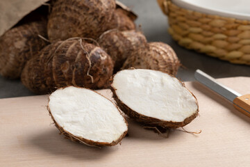 Fresh whole and halved taro vegetable on a cutting board 
