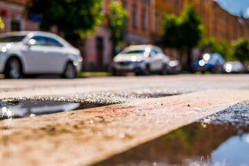 Sunny day after rain in the city, parked in the street car. Close up view from the puddle level...