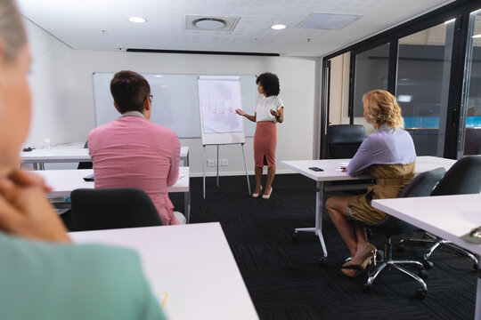 African american woman giving a presentation to her office colleagues in meeting room at office