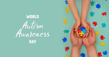 World autism awareness day. Understanding - love concept. The hands of an autistic father and child hold a colorful puzzle on blue background. ASD. Heart of puzzles. Banner. Layout