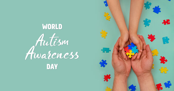 World autism awareness day. Understanding - love concept. The hands of an autistic father and child hold a colorful puzzle on blue background. ASD. Heart of puzzles. Banner. Layout