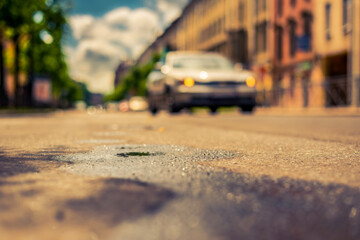 Sunny day after rain in the city, the car rides along the road. Close up view from the asphalt level