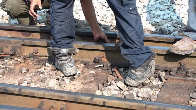 The worker tightened the screws on the rail with a large wrench in hand.	
